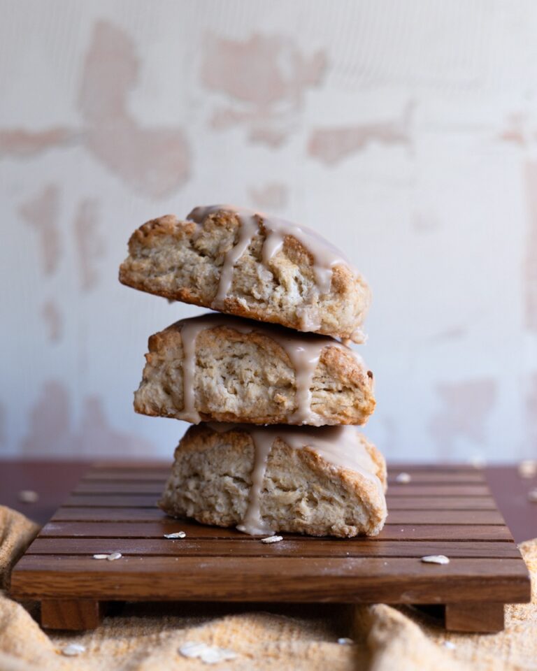 three maple oatmeal scones stacked on a wooden trivet